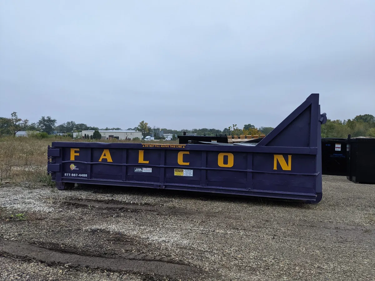 Contenedor roll-off de 10 yardas de Falcon Green Resources colocado en un patio de grava