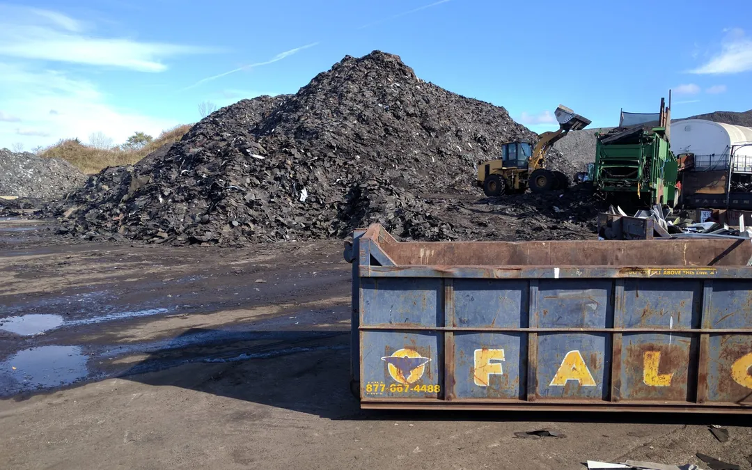 Gran montón de material recuperado detrás de un contenedor de Falcon Green Resources