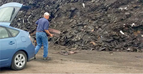 Hombre descargando tejas viejas de un automóvil en la pila de reciclaje de tejas